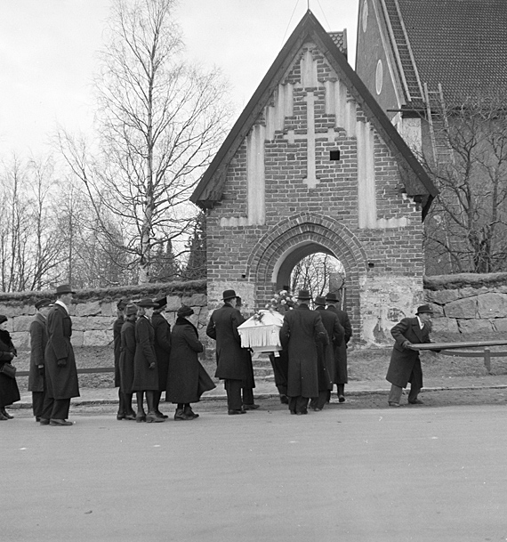 Svartvit bild från 1940-talet. Ett begravningståg är på väg in i kyrkan.