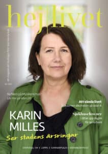 En porträttbild av Karin Milles. Hon har brunt halvlångt hår, nästan i page. Hon är klädd i en grön kappa med svart tröja under.