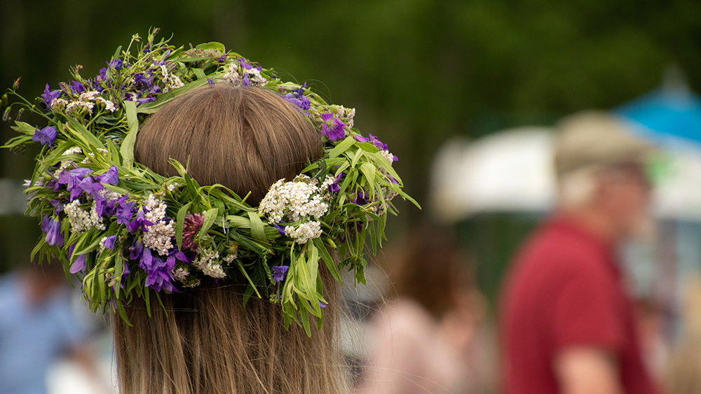 Flicka med blomsterkrans i håret, fotograferat bakifrån